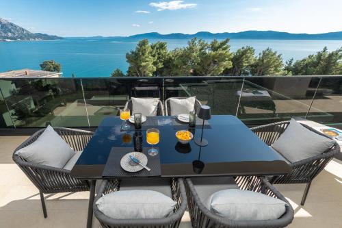 a table and chairs on a balcony with a view of the water at Villa Laganini Apartment 2&4 in Podaca