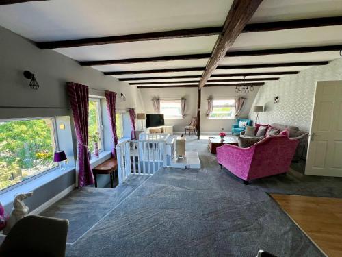 a living room with pink furniture and a staircase at The Loft @ Brighouse in Brighouse