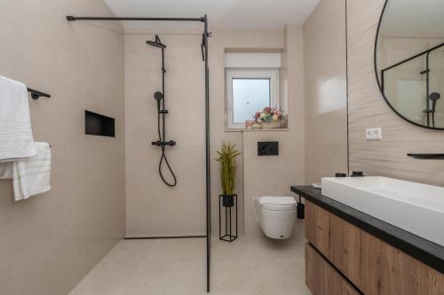 a bathroom with a shower and a toilet and a sink at Villa Laganini Apartment 2&4 in Podaca
