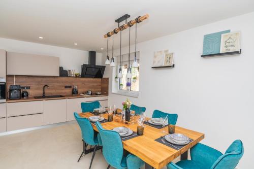 a kitchen and dining room with a wooden table and blue chairs at Villa Laganini Apartment 2&4 in Podaca