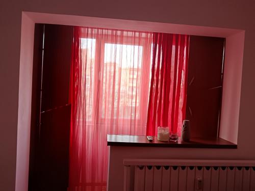 a window with red curtains in a room at Apartament 1 camera zona liniștită in Drobeta-Turnu Severin