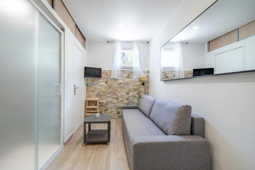 un salon avec un canapé et un mur de briques dans l'établissement Port de Nice, Charmant studio, à Nice