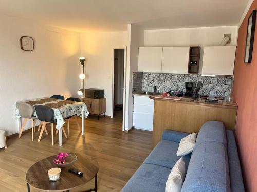 un salon avec un canapé bleu et une cuisine dans l'établissement Appartement cosy - centre-ville, à Boulogne-sur-Mer