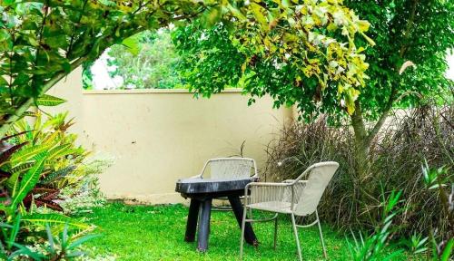 two chairs and a table in the grass at Airport Shoebill Hotel in Entebbe