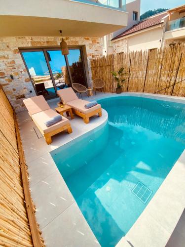a swimming pool with two lounge chairs and a house at Amo Golden Suites in Chrysi Ammoudia