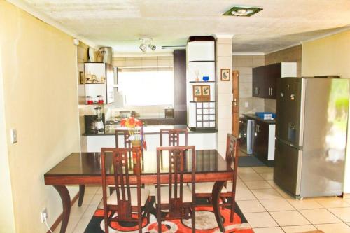 a kitchen with a table with chairs and a refrigerator at Ezulwini Zululami in Ezulwini