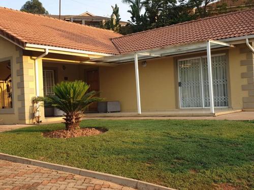 a house with a palm tree in the front yard at Ezulwini Zululami in Ezulwini