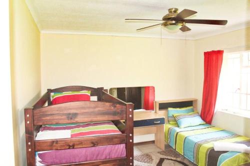 a bedroom with two beds and a ceiling fan at Ezulwini Zululami in Ezulwini