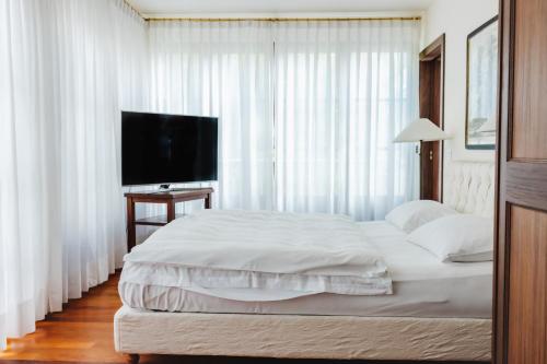 a bedroom with a large white bed and a television at Hotel Villa Irma in Merano