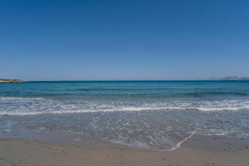 a sandy beach with the ocean in the background at Black Sand in Moutsouna Naxos