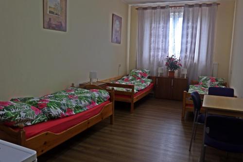 a room with two beds and a table and chairs at Hotel Dworek in Wrocław