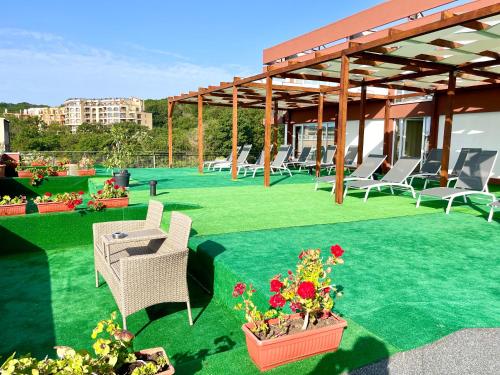 a patio with chairs and flowers on the grass at BSA Gradina Hotel & Aquapark - All Inclusive in Golden Sands