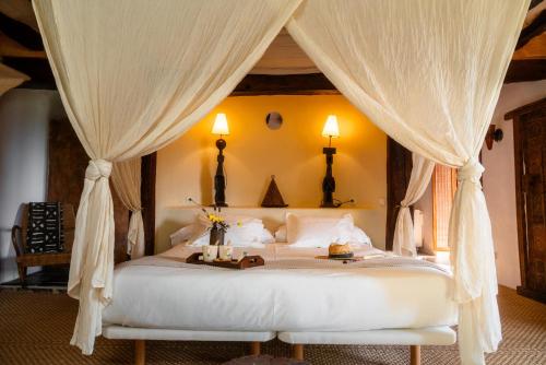a bedroom with a canopy bed with white curtains at Can Serola in Sales del Llierca