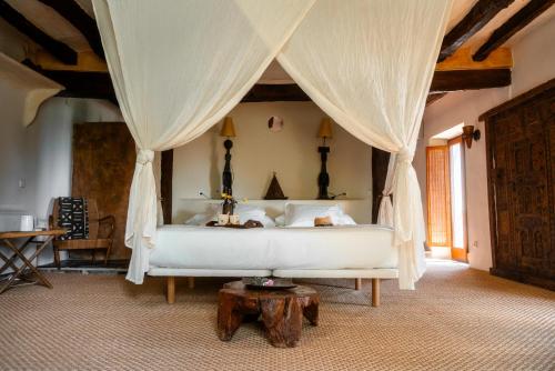 ein Schlafzimmer mit einem weißen Bett mit Vorhängen und einem Tisch in der Unterkunft Can Serola in Sales del Llierca