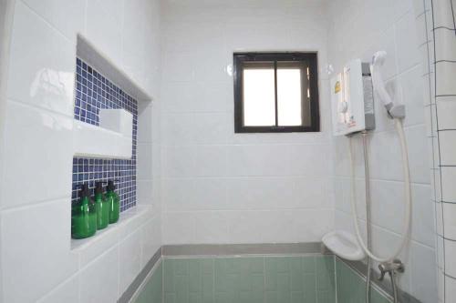 a bathroom with a tub and a shower with a window at 57 Hidden House BKK Chinatown in Bangkok