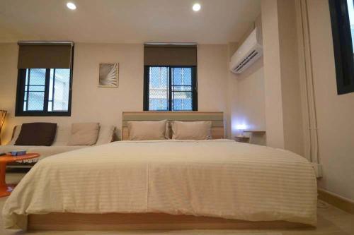 a bedroom with a large white bed and two windows at 57 Hidden House BKK Chinatown in Bangkok
