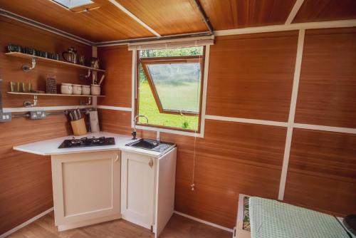 a small kitchen with wooden walls and a window at Leto Shepherds Hut By Airpremier in Alfriston