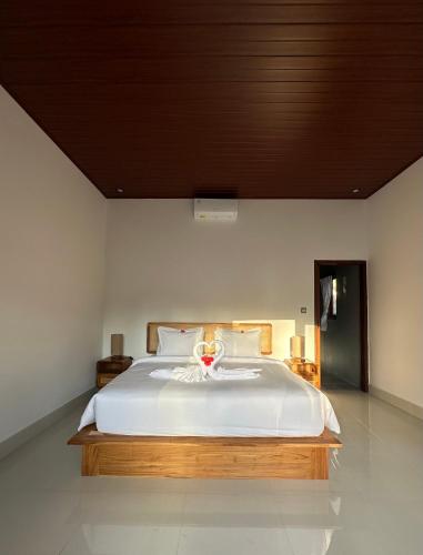 a bedroom with a large white bed with a wooden headboard at Made Putu homestay in Sidemen