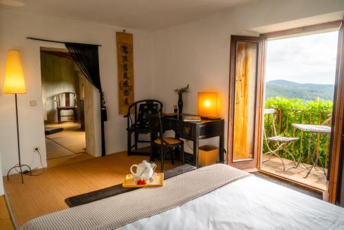 a bedroom with a bed and a desk and a balcony at Can Serola in Sales del Llierca