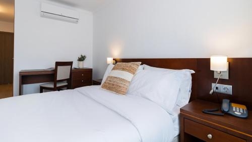 a bedroom with a white bed and a desk with a chair at Albergaria Quim Barreiros in Vila Praia de Âncora