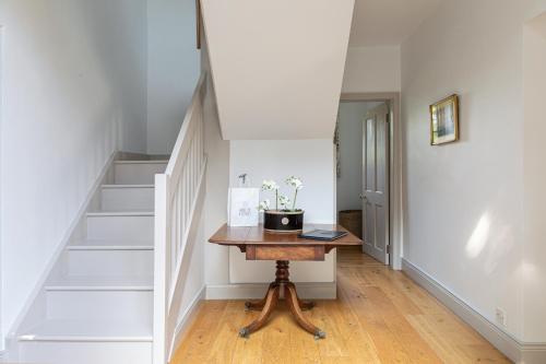 a hallway with a wooden table and stairs at Charming Georgian Coach House in Hexham