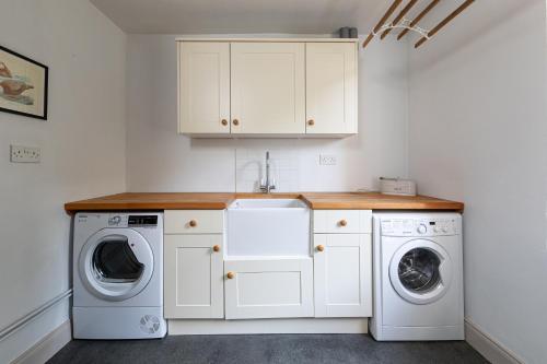 a white laundry room with a washer and dryer at Charming Georgian Coach House in Hexham