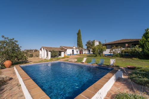 a swimming pool in a yard with chairs and a house at Monte das Acácias in Santo António do Baldio
