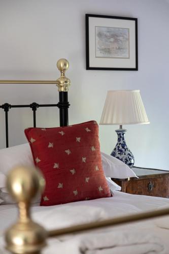 a bed with a red pillow and a table with a lamp at Charming Georgian Coach House in Hexham