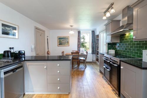 a kitchen with white cabinets and black counter tops at Charming Georgian Coach House in Hexham