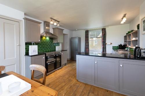 a kitchen with gray cabinets and a wooden table at Charming Georgian Coach House in Hexham
