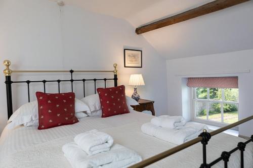 a bedroom with a large bed with red pillows at Charming Georgian Coach House in Hexham