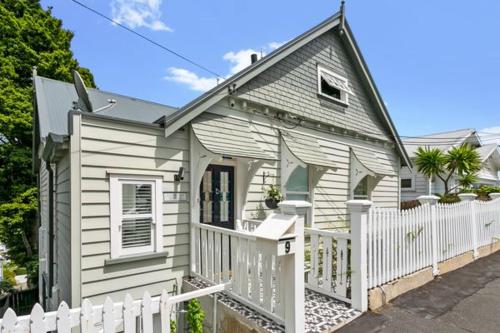a small white house with a white fence at Auckland City Villa in Auckland