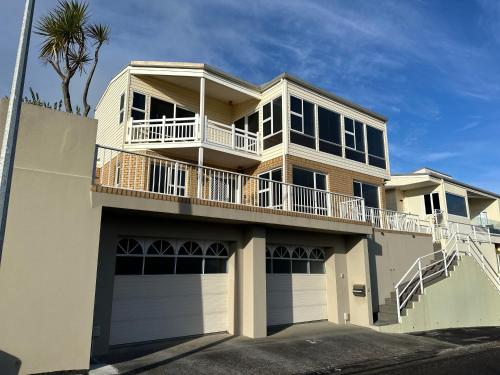 a white house with a balcony and a porch at Hamblyn Heights Stunning Seaviews in New Plymouth in New Plymouth