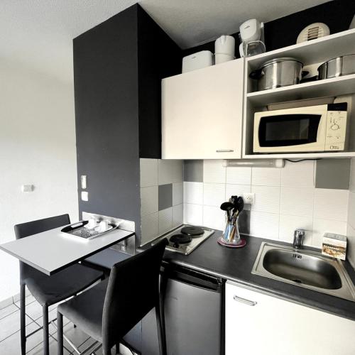 une petite cuisine avec un évier et un micro-ondes dans l'établissement Casa du sud, à Béziers