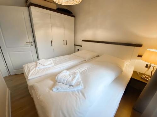 a bedroom with a white bed with towels on it at Steilufer Appartments in Timmendorfer Strand