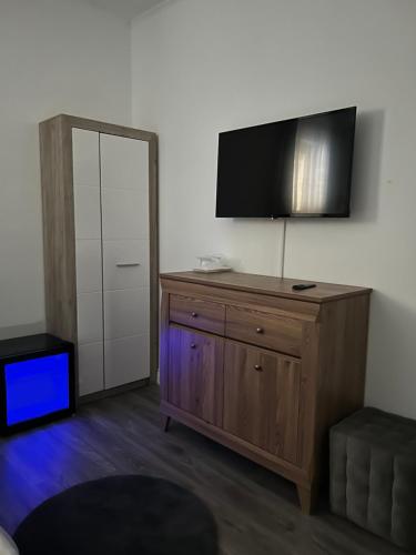 a room with a wooden dresser with a flat screen tv at Pensiunea Le Patrick in Afumaţi
