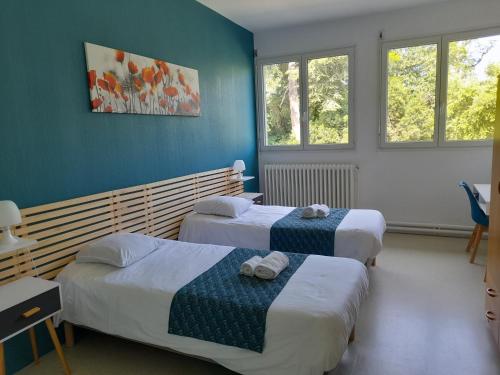 2 łóżka w pokoju z niebieskimi ścianami i oknami w obiekcie Centre Louis Ormières w mieście Montauban
