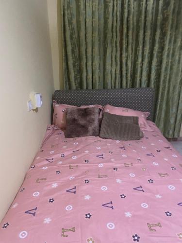 a bed with a pink comforter and pillows on it at Villa de chez nous in North Legon