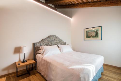 a bedroom with a white bed and a table with a lamp at Hotel Ristorante Magia del Brenta in Fiesso dʼArtico