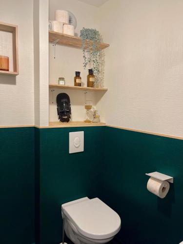 La salle de bains est pourvue de toilettes et d'un mur vert. dans l'établissement Cosy-Rent Appartement de standingparking Neudorf, à Strasbourg