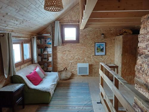 ein Wohnzimmer mit einer Couch und einem Fenster in der Unterkunft La Cabane des 2 Sœurs (chalet 4-6 personnes) in Les Ougiers