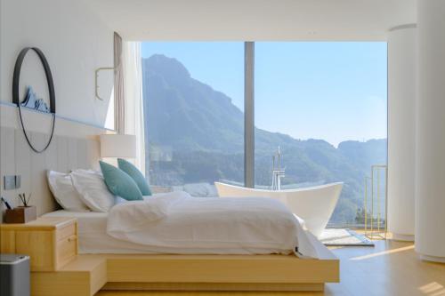 a bedroom with a bed and a large window at XMAN Sunrise Peaks Resort--Free Pick-up in Zhangjiajie