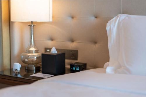 a hotel room with a bed with a lamp and a clock at The Langham, Hefei in Hefei