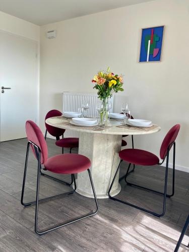 - une table avec des chaises rouges et un vase de fleurs dans l'établissement Cosy-Rent Appartement de standingparking Neudorf, à Strasbourg