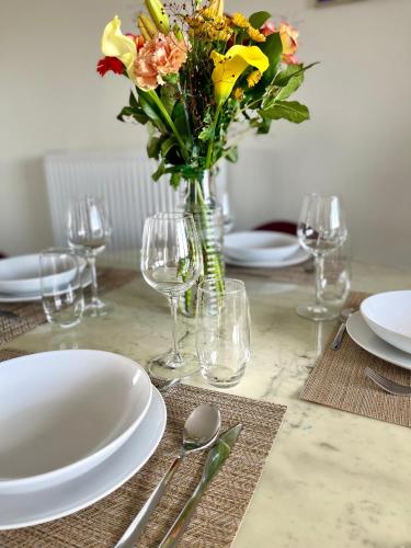 une table avec des assiettes et un vase de fleurs dans l'établissement Cosy-Rent Appartement de standingparking Neudorf, à Strasbourg