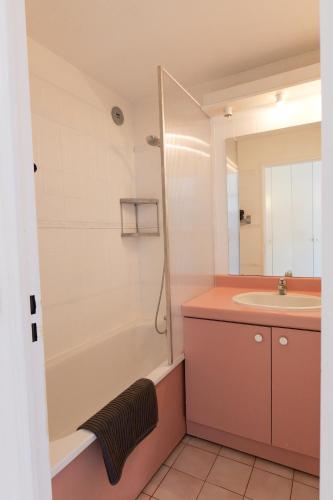 une salle de bain avec un lavabo, une baignoire et un miroir dans l'établissement Appartement C 529 piscine front de mer, à Sète