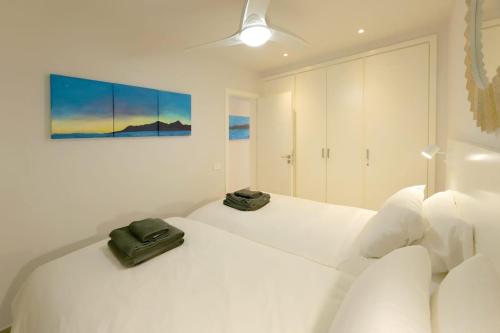 a white bedroom with two white beds and a painting at Lanzarote Apartment Rental Harbour View in Tías