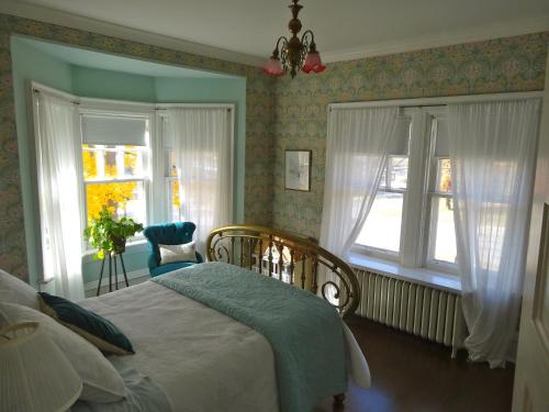 um quarto com uma cama e duas janelas em The Captain's House heritage bed & breakfast em Midland