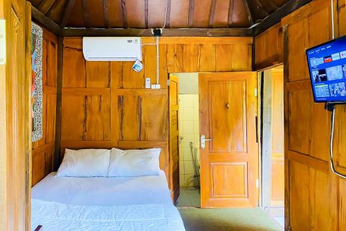 1 dormitorio con cama, puerta y TV en Lembah Mbalong Resort Mitra RedDoorz Near Exit Tol Singosari en Blimbing