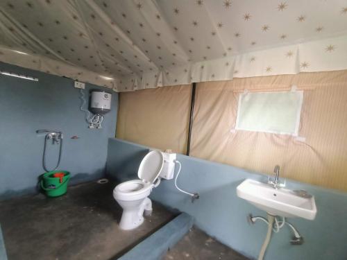 a small bathroom with a toilet and a sink at DIV ADVENTURE CAMP in Dharamshala